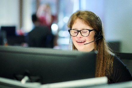 A young woman with a headset on in an office.