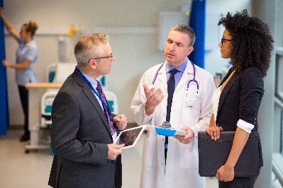 2 people talking to a doctor in a hospital.