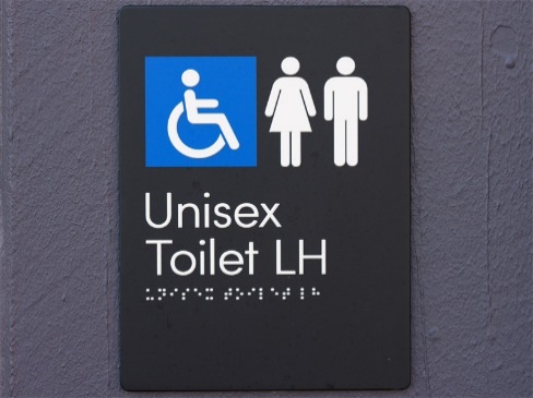 A sign with the disability symbol and unisex symbol. It has Unisex Toilet LH printed on it and Braille underneath.