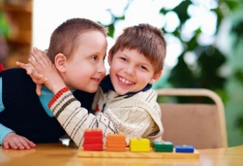 2 young boys with disabilities hugging each other and smiling.