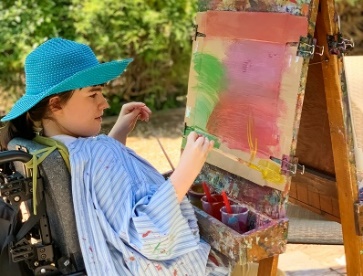 A person with disability painting on a canvas.