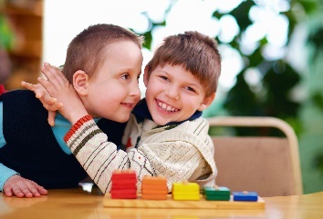 2 young boys with disabilities hugging each other smiling.