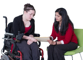 A woman showing a woman in a wheelchair information on a tablet.