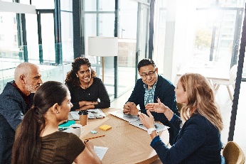 A group of people sitting at a table having a meeting. 