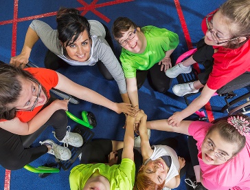 A group of people with disability putting their hands into a circle.