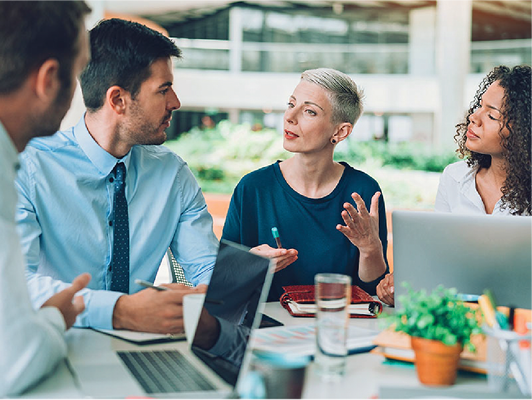 A group of people with laptop computers having a discussion.