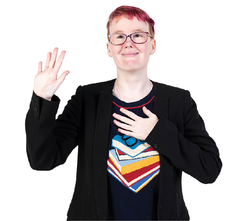 An Autistic person smiling with one hand up, and the other hand on their chest.