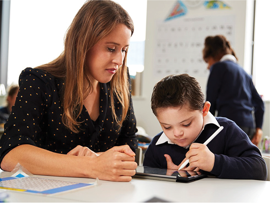 A teacher supporting a child in the classroom.