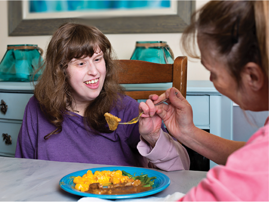 A worker supporting an Autistic person to eat.